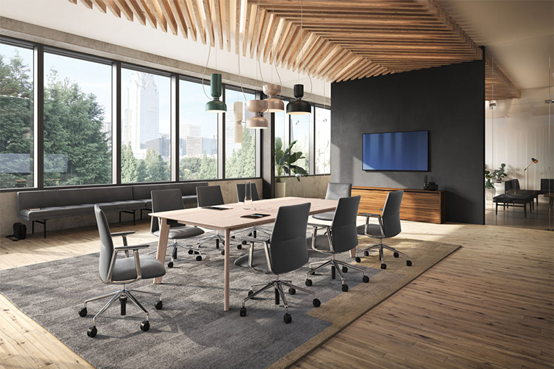 Salle de conférence moderne et lumineuse avec grande table rectangulaire en bois clair, chaises ergonomiques grises sur roulettes et plafond en bois design, idéale pour les réunions collaboratives dans un espace de travail contemporain.