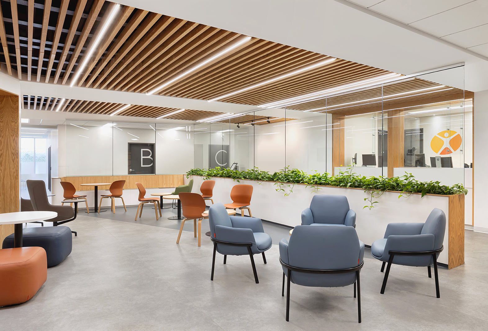 fauteuils en tissu bleu et chaises coquille en plastique de couleur rouille dans une salle d'attente d'une clinique médicale