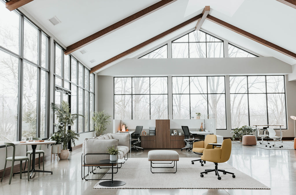 Espace de bureau moderne et lumineux avec mobilier ergonomique, postes collaboratifs et grandes fenêtres vitrées.