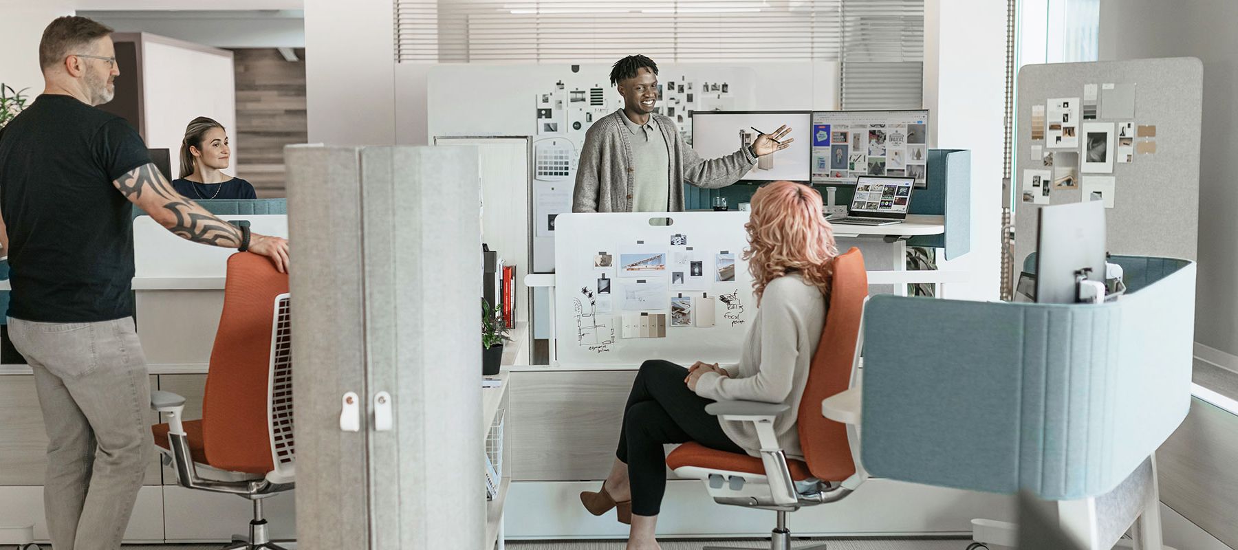 quatre personnes en interaction dans des postes de travail en aire ouverte