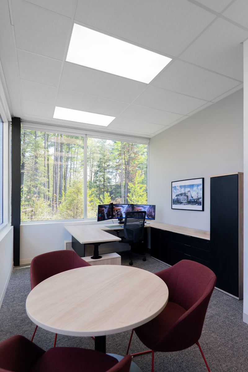 Bureau privé avec poste de travail triple écrans, table ronde et chaises bordeaux, vue sur forêt — Beauce Atlas