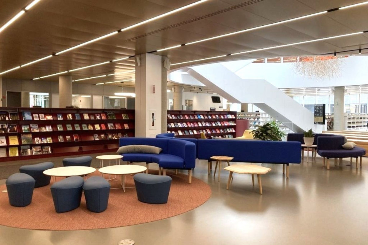 Espace lounge bibliothèque avec mobilier de bureau moderne - Canapés bleus, poufs et tables basses design