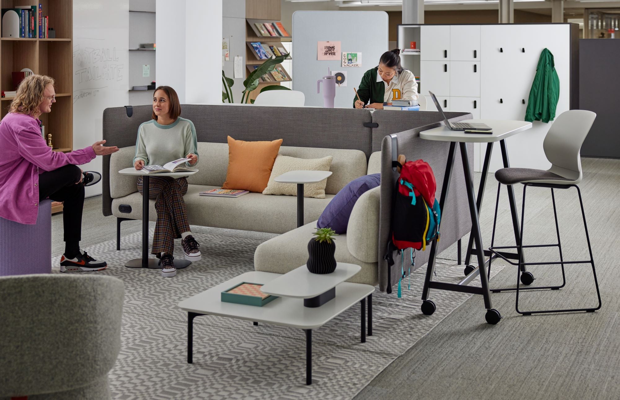 Espace collaboratif moderne avec banquettes, tables basses et postes de travail. Étudiants et collègues échangent dans un environnement flexible et convivial.