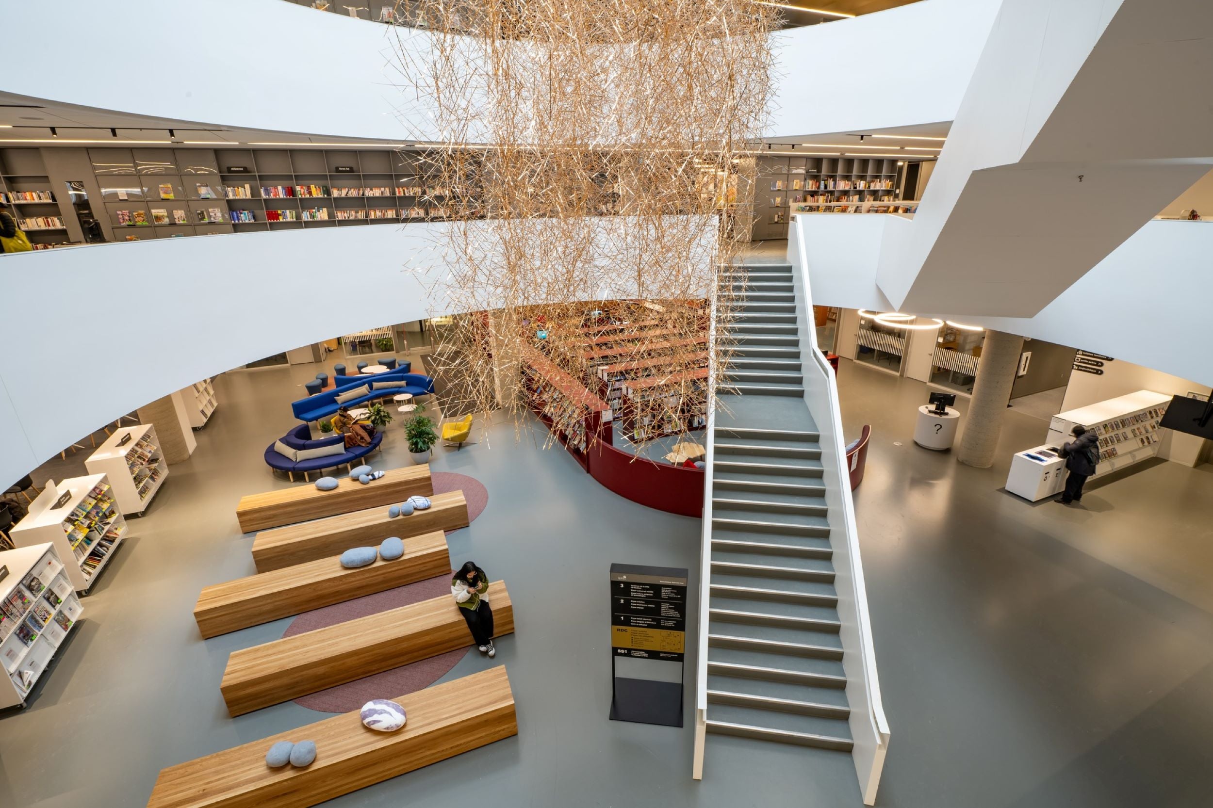 Bibliothèque moderne avec escalier central, mobilier de bureau contemporain et espaces de lecture - Design d'intérieur professionnel