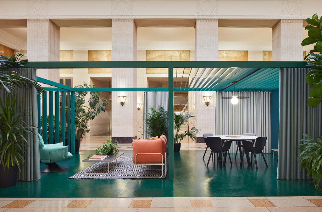 Espace de travail design avec cloisons modernes, mobilier coloré, coin salon confortable et salle de réunion élégante.