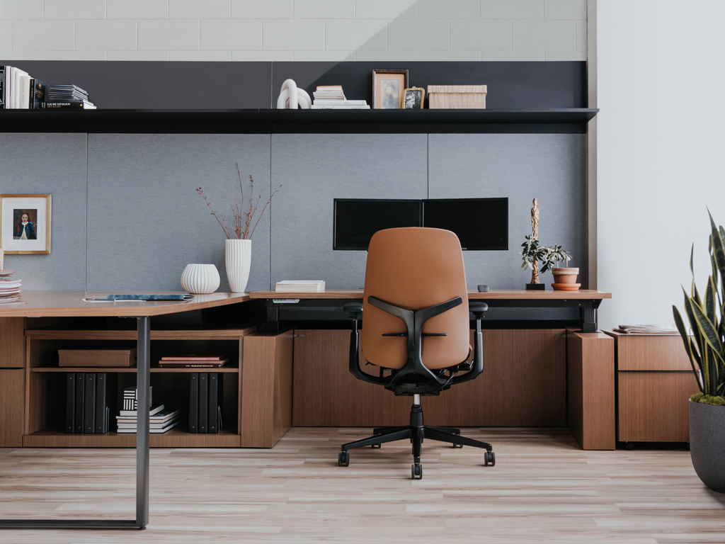 Bureau moderne avec chaise ergonomique en cuir, grand poste de travail en bois, rangement intégré et décoration soignée.