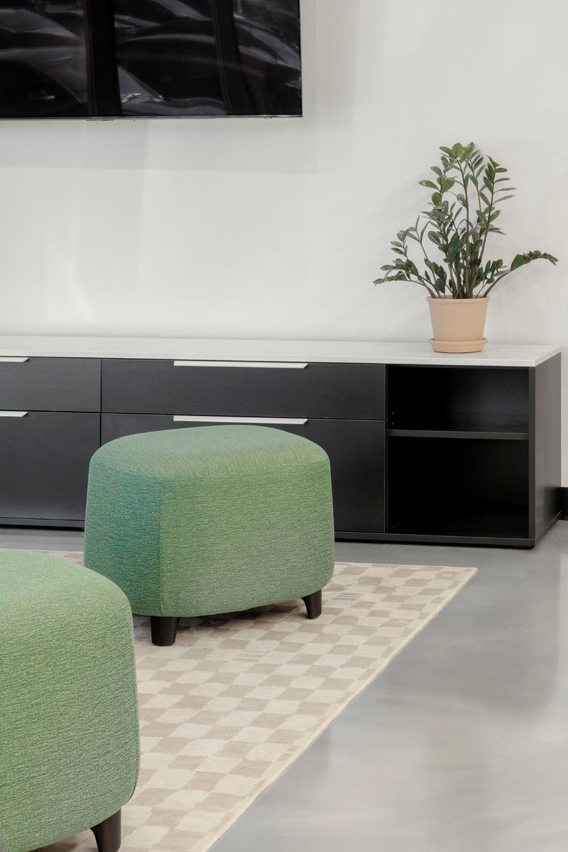 Mobilier de bureau moderne avec meuble de rangement noir mat à tiroirs multiples et pouf d'appoint vert menthe pour espace détente. Solution de rangement élégante combinant fonctionnalité et design contemporain, parfaite pour aménager un coin repos professionnel accueillant.