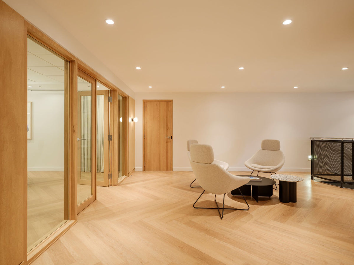 Espace d'attente bureau avec fauteuils ergonomiques blancs et portes vitrées bois