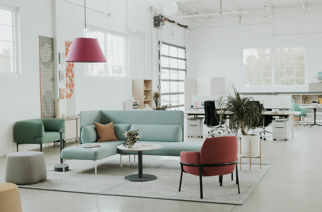 Espace de bureau lumineux avec mobilier design coloré, coin lounge moderne, plantes décoratives et postes de travail collaboratifs.