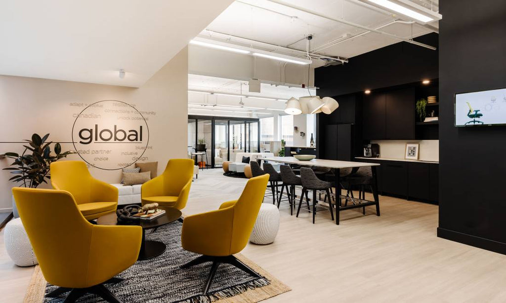 Espace de bureau moderne avec fauteuils jaunes design, coin cuisine noir élégant, grande table haute et ambiance conviviale.